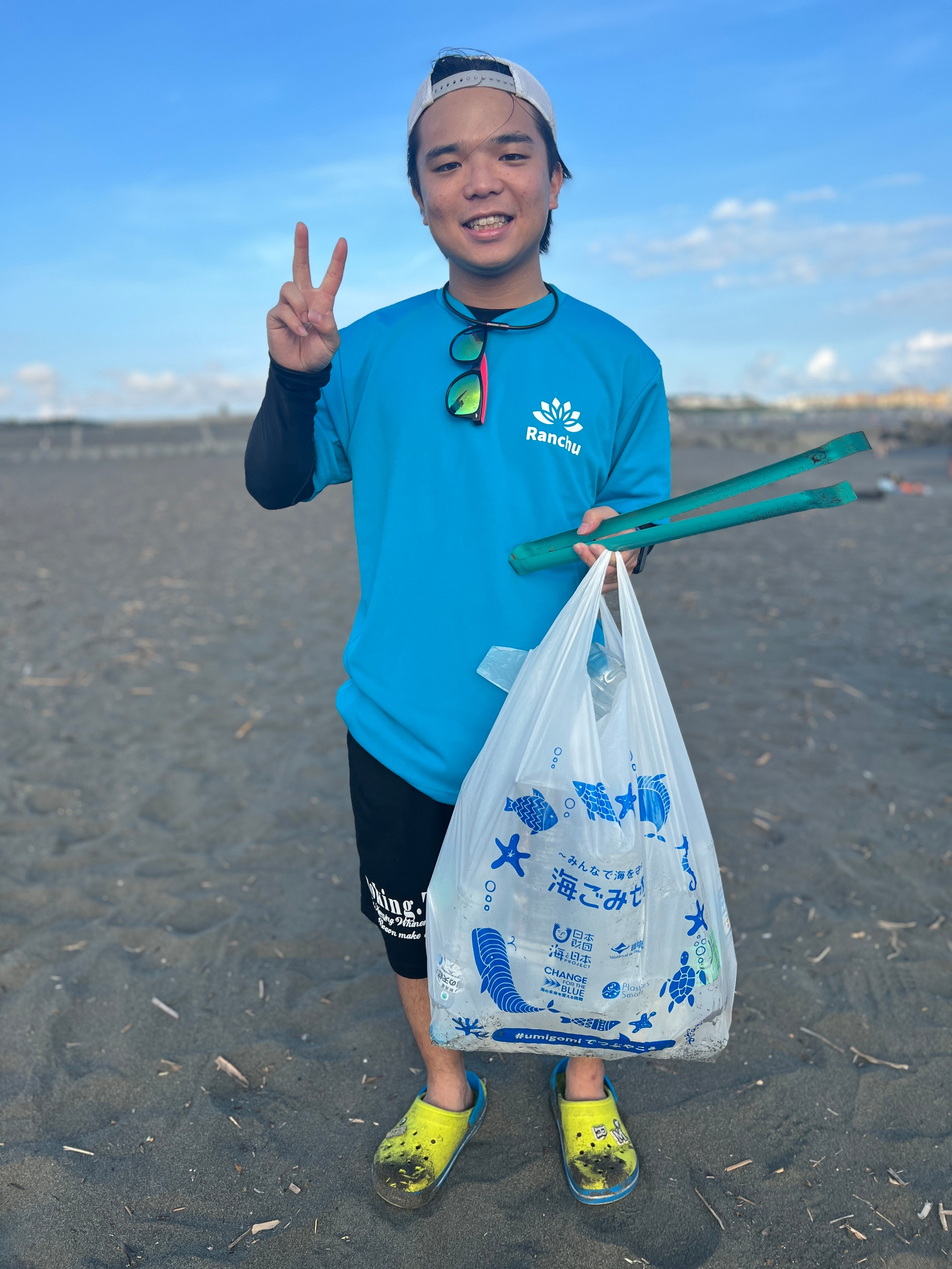 大学3年生が鵠沼海岸で天気の良い日にトングとゴミ袋で回収した海洋ごみと一緒に撮った記念写真